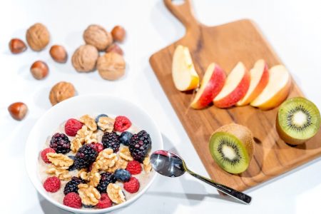 A nutritious breakfast bowl featuring fresh berries and walnuts, served with sliced fruit and kiwi.