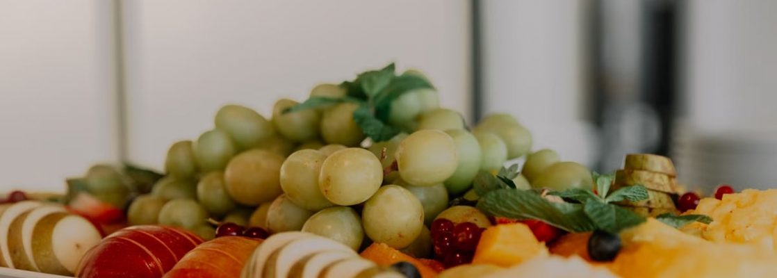 A vibrant assortment of fruits including grapes, apples, and berries on a white tray.