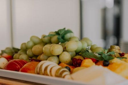 A vibrant assortment of fruits including grapes, apples, and berries on a white tray.